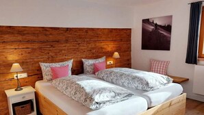 A double bed with floral bedding, two bedside lamps, a wooden headboard, and a framed picture on the wall. - Apartment in Bad Hindelang-bad Oberdorf (Bad Hindelang)