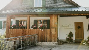 A wooden building with a sloped roof, a wooden porch with flower boxes, and a sign that reads "Berghaus Ferienwohnungen." - Apartment in Bad Hindelang-bad Oberdorf (Bad Hindelang)