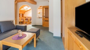 A cozy living room with a sofa, a small table, a TV, and wooden furniture. - Beautiful Apartment With Stunning View (Mittersill)