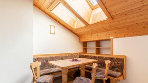 A cozy corner with a wooden table and bench, a skylight, and a small wall-mounted light. - Beautiful Apartment With Stunning View (Mittersill)