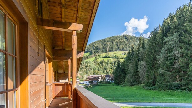 A wooden cabin with a balcony overlooking a green valley and forested hills. - Beautiful Apartment With Stunning View (Mittersill)