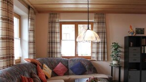 A cozy living room with a sofa, a coffee table, and a bookshelf. - Kreuzwiesen Comfortable Holiday Residence (Missen-Wilhams)