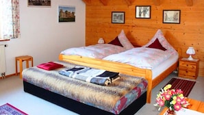 A cozy bedroom with a wooden ceiling, a bed with a patterned duvet, a small bedside table, and a nightstand. - Kreuzwiesen Comfortable Holiday Residence (Missen-Wilhams)