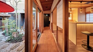 Un pasillo con suelo de madera y puertas de cristal que dan a un comedor.
