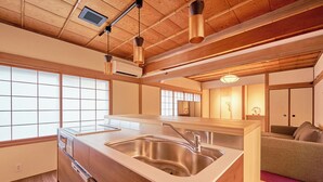Una cocina moderna con armarios de madera, un lavamanos de acero inoxidable e iluminación colgante.