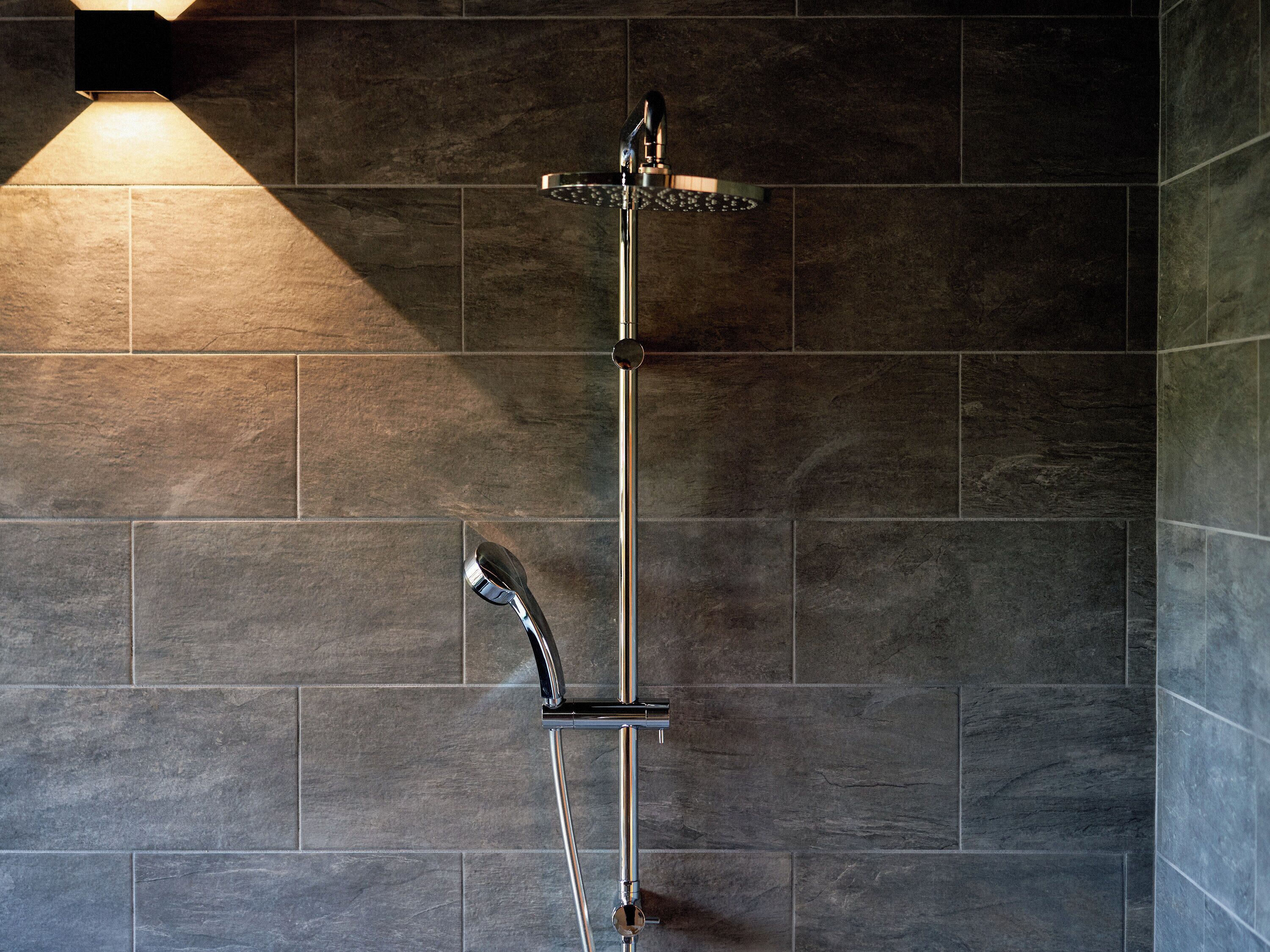 A shower with a chrome faucet and a handheld showerhead mounted on a wall.