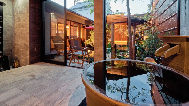 Un interior moderno con un gran ventanal que da a un jardín, muebles de madera y una fuente de agua reflectante.