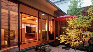 Una casa tradicional japonesa con puertas correderas, una terraza de madera y un pequeño jardín con un farol de piedra.