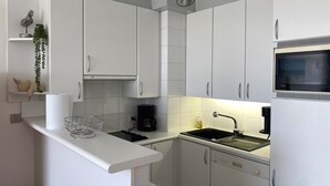 Cocina moderna con gabinetes blancos, microondas integrado y cafetera.