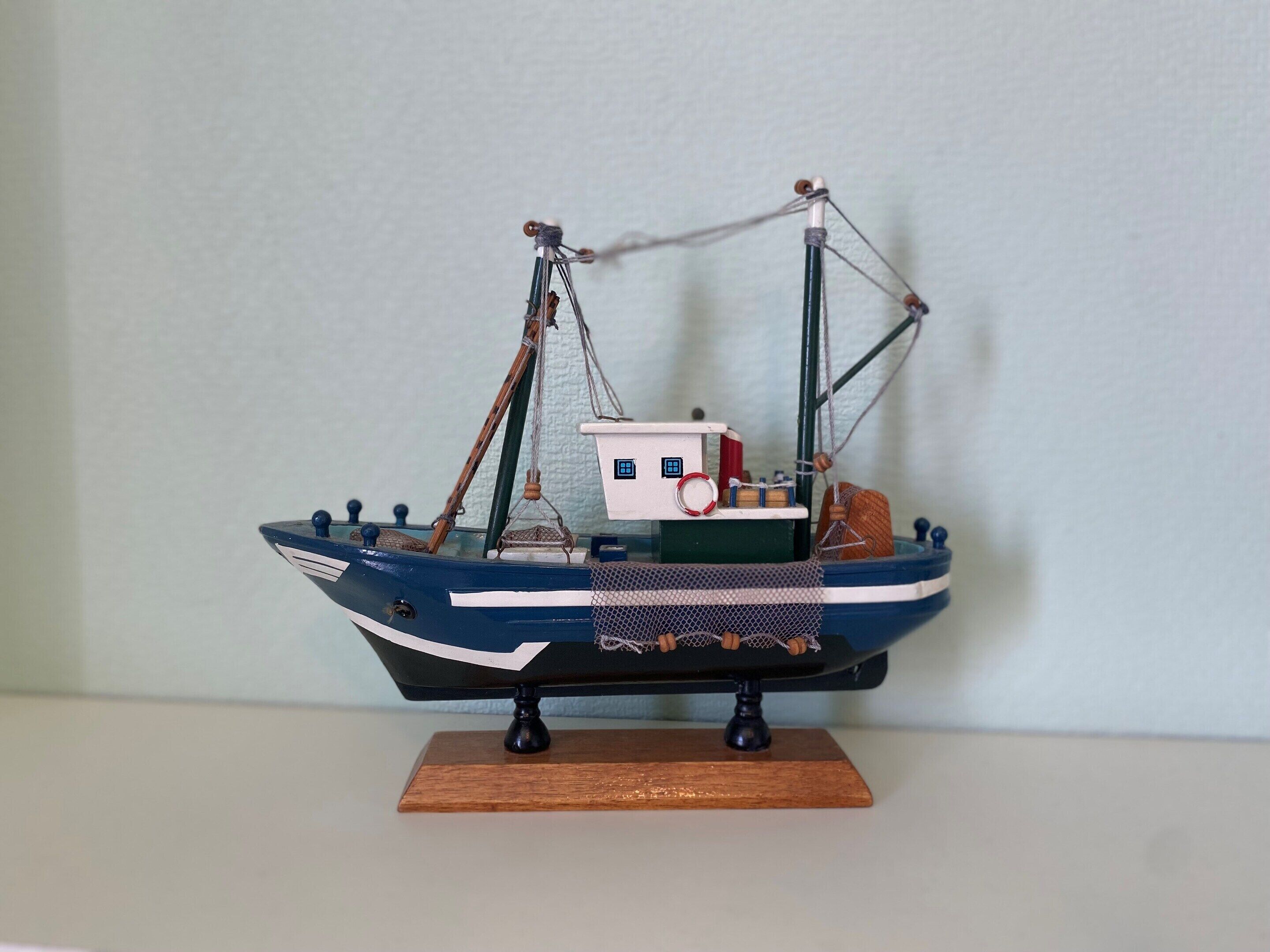 A model of a fishing boat with a cabin, net, and mast.