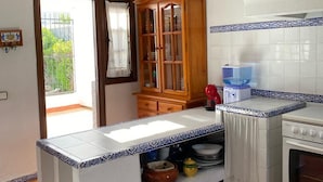 Een keuken met een betegelde spatwand, houten kastjes en een inbouwoven.