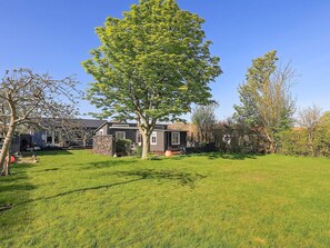 Il s’agit d’une propriété résidentielle dotée d’une pelouse bien entretenue, d’un grand arbre et d’une maison à la façade en pierre.