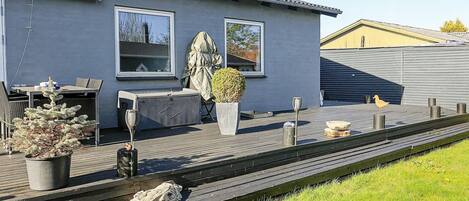 Een modern huis met een terras, tuinmeubilair en een plant in een pot.