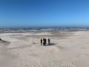 A beach with a clear sky and a few people standing on the sand. - 4 Star Holiday Home in Saltum (Saltum)