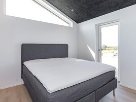 Un dormitorio con cama, tragaluz y puerta que da al exterior.