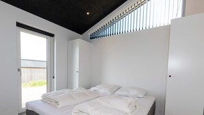 A bedroom with a bed, a wardrobe, and a window. - 4 Star Holiday Home in Saltum (Saltum)