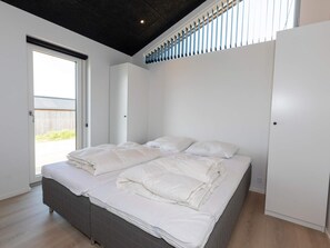 A bedroom with a bed, a wardrobe, and a window. - 4 Star Holiday Home in Saltum (Saltum)