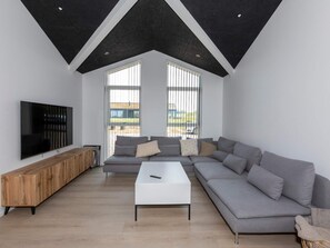 A modern living room with a sectional sofa, a flat-screen TV, and a coffee table.