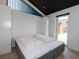 Un dormitorio moderno con una cama grande, paredes blancas y vistas al exterior.