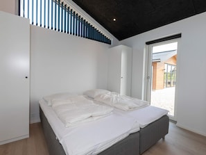 Un dormitorio moderno con una cama grande, paredes blancas y vistas al exterior.