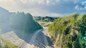 Ein Kiesweg schlängelt sich durch eine grüne Landschaft, ein Gebäude ist links zu sehen.