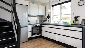 A modern kitchen with white cabinets, a stainless steel refrigerator, a built-in oven, and a large window with natural light. - 7 Person Holiday Park Home in Ebeltoft (Ebeltoft)