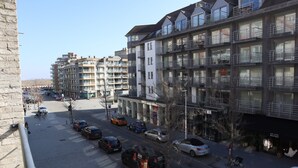 A multi-story residential building with balconies, a parking area, and a storefront with a sign. - Apartment in Nieuwpoort Near Sandy Shores (Nieuwpoort)