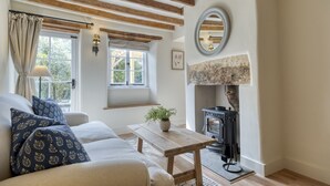 Uma sala de estar aconchegante com sofá, mesa de madeira, lareira e janela com cortinas.