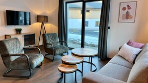 A modern living room with a sofa, two armchairs, a coffee table, and a TV. - Chalet Near Lake Pressegger and Nassfeld ski Area (Hermagor-Pressegger See)