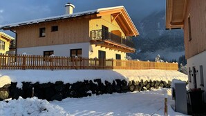 A wooden chalet with a balcony, stone wall, and snow-covered ground. - Chalet Near Lake Pressegger and Nassfeld ski Area (Hermagor-Pressegger See)