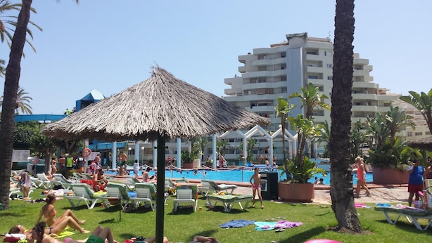 A resort with a swimming pool, lounge chairs, and a thatched-roof structure. - Apartment With Beach View (Benalmádena)