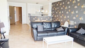 A modern living room with a black leather sofa, a white coffee table, and a patterned wall. - Attic Apartment Nieuwpoort by the Sea Wall (Nieuwpoort)