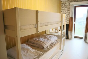 Ein Stockbett in einem Zimmer mit Fenster und Vorhängen.