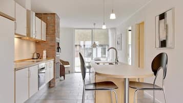 A modern kitchen with a central island, stainless steel appliances, and a brick accent wall.