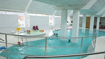 Una piscina interior con varias pistas de natación, una zona de hidromasaje separada y una terraza de visualización con barandillas.