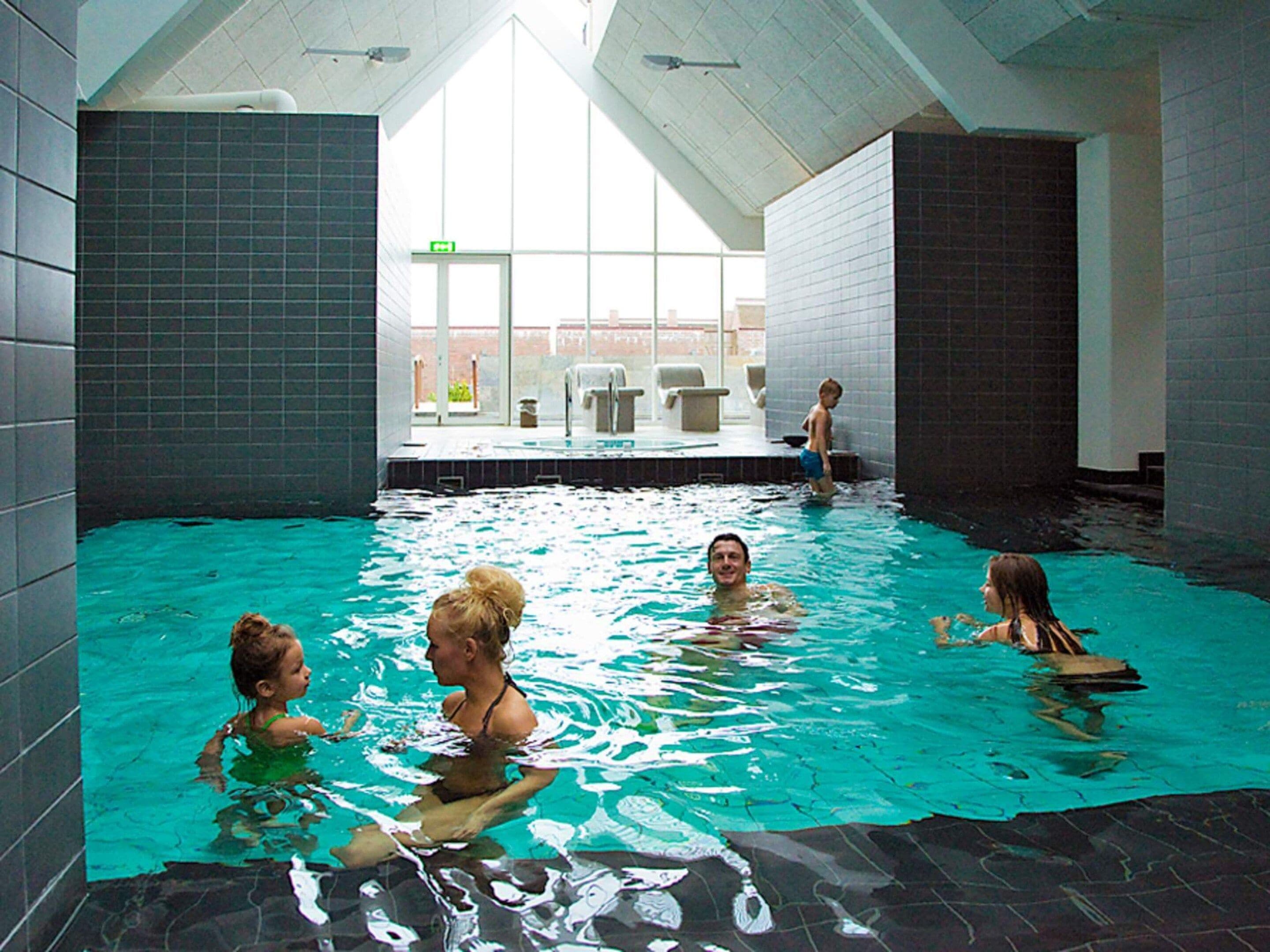 An indoor swimming pool with tiled walls and a sloped ceiling.