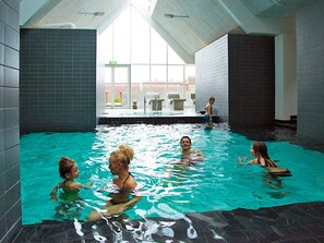 Una piscina interior con paredes de azulejos y techo inclinado.