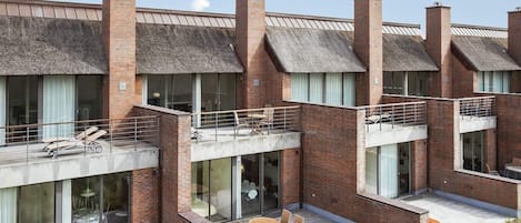 A modern building with multiple floors, large windows, and outdoor seating areas.