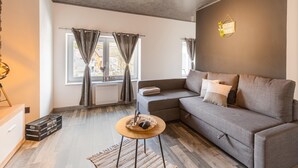 Un salon moderne avec un canapé gris, une petite table ronde et un radiateur.