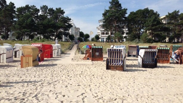 Una playa con cabañas de playa y un camino que lleva a un edificio.