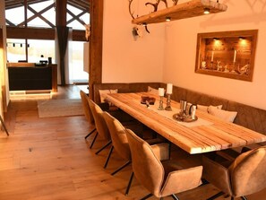 Un comedor con una mesa de madera larga, sillas acolchadas y una decoración rústica que incluye ciervos y velas.