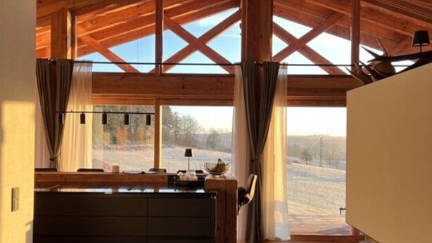 Une pièce spacieuse avec un plafond haut et de grandes fenêtres, un plafond en bois et une cheminée en pierre.