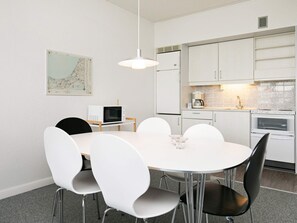 A modern kitchen with white cabinets, a microwave, a coffee maker, and a dining table with chairs.