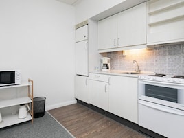 Cocina compacta con armarios blancos, microondas, cafetera y estufa.