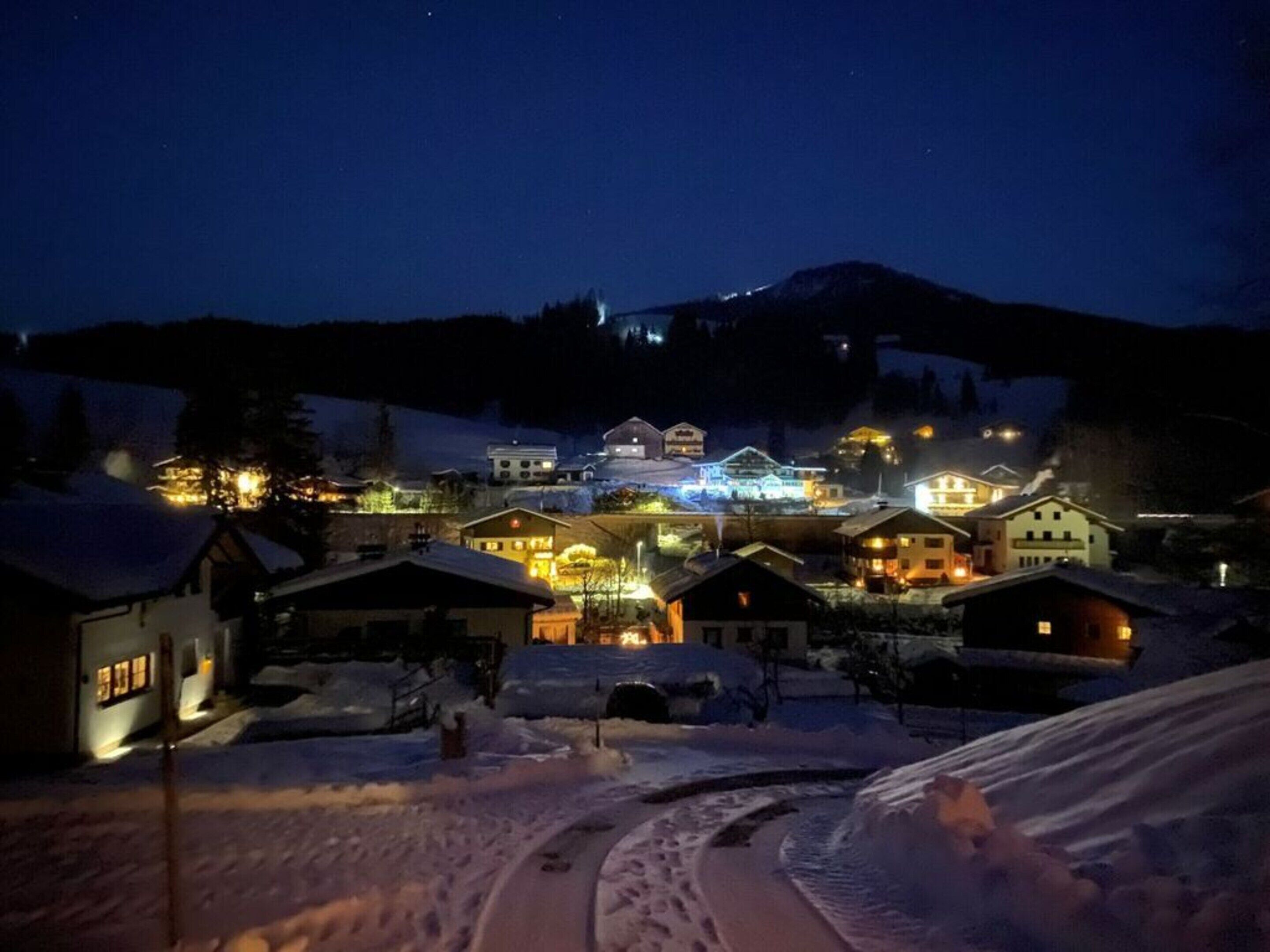 Un pueblo cubierto de nieve con edificios iluminados de noche.