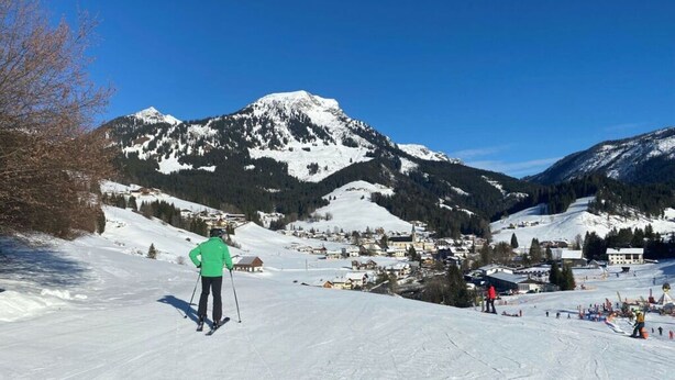 A ski resort with a clear view of a mountain, skiers, and a small village in the background. - Skiblickhaus Comfortable Holiday Residence (Russbach am Pass Gschuett)