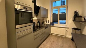 Une cuisine compacte dotée d’un four encastré, d’une plaque de cuisson et d’une fenêtre située au-dessus de l’évier.