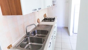 Una cocina con un lavamanos doble, estufa y armarios blancos.