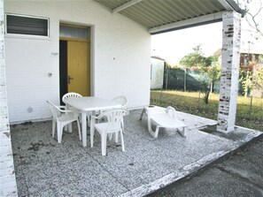 A white building with a covered patio area featuring a table and chairs.