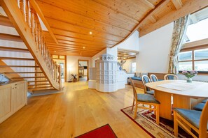 A spacious living area with a wooden staircase, a central white column, and a dining table with chairs. - Chalet in Mittersill Near Ski Slopes (Mittersill)